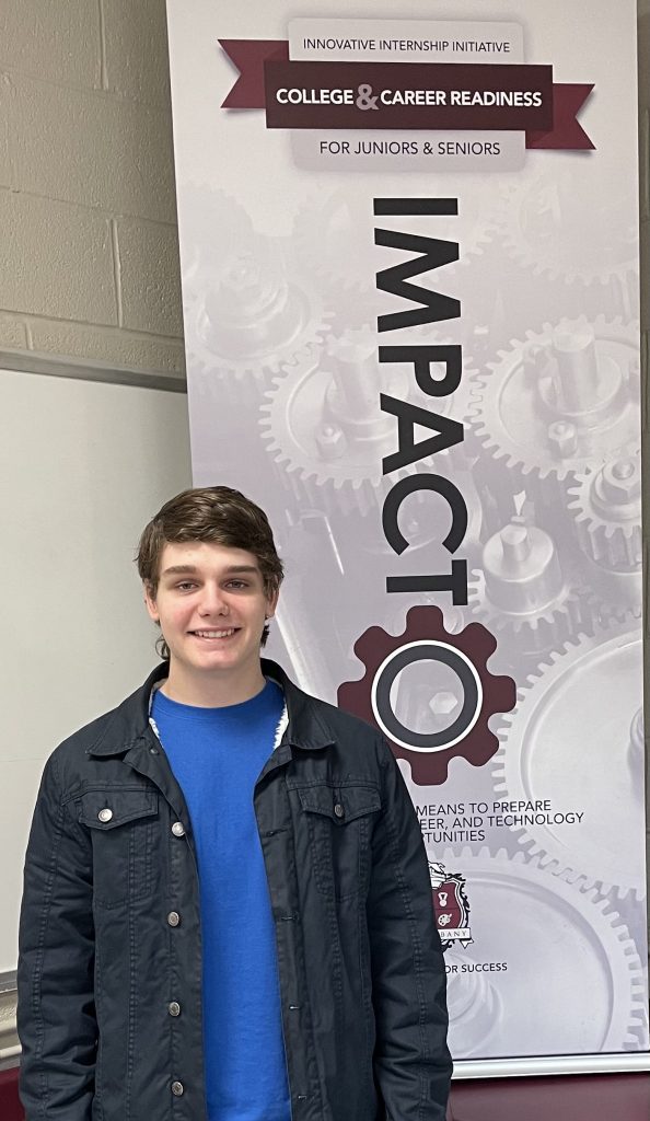 Picture of Chris Brennan in front of IMPACTO banner