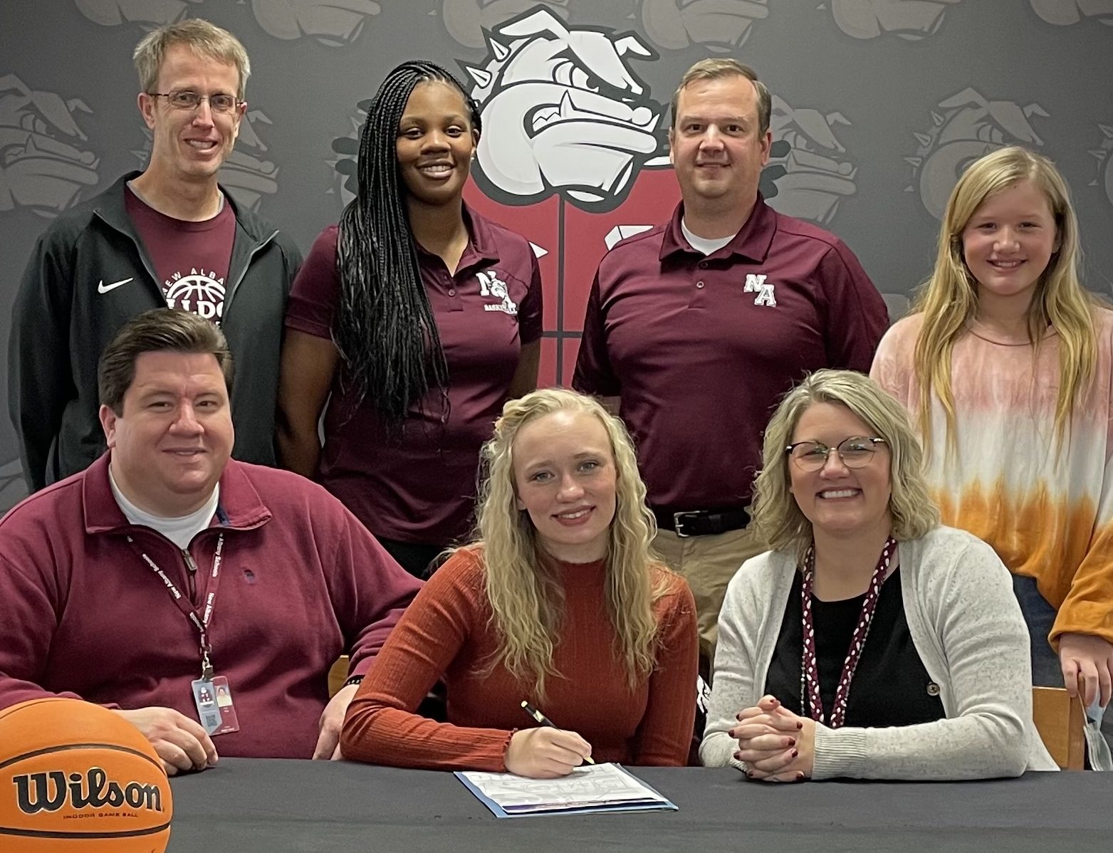 Ella Tyer signing with Blue Mountain College basketball - surrounded by family, coaches, and school administration.