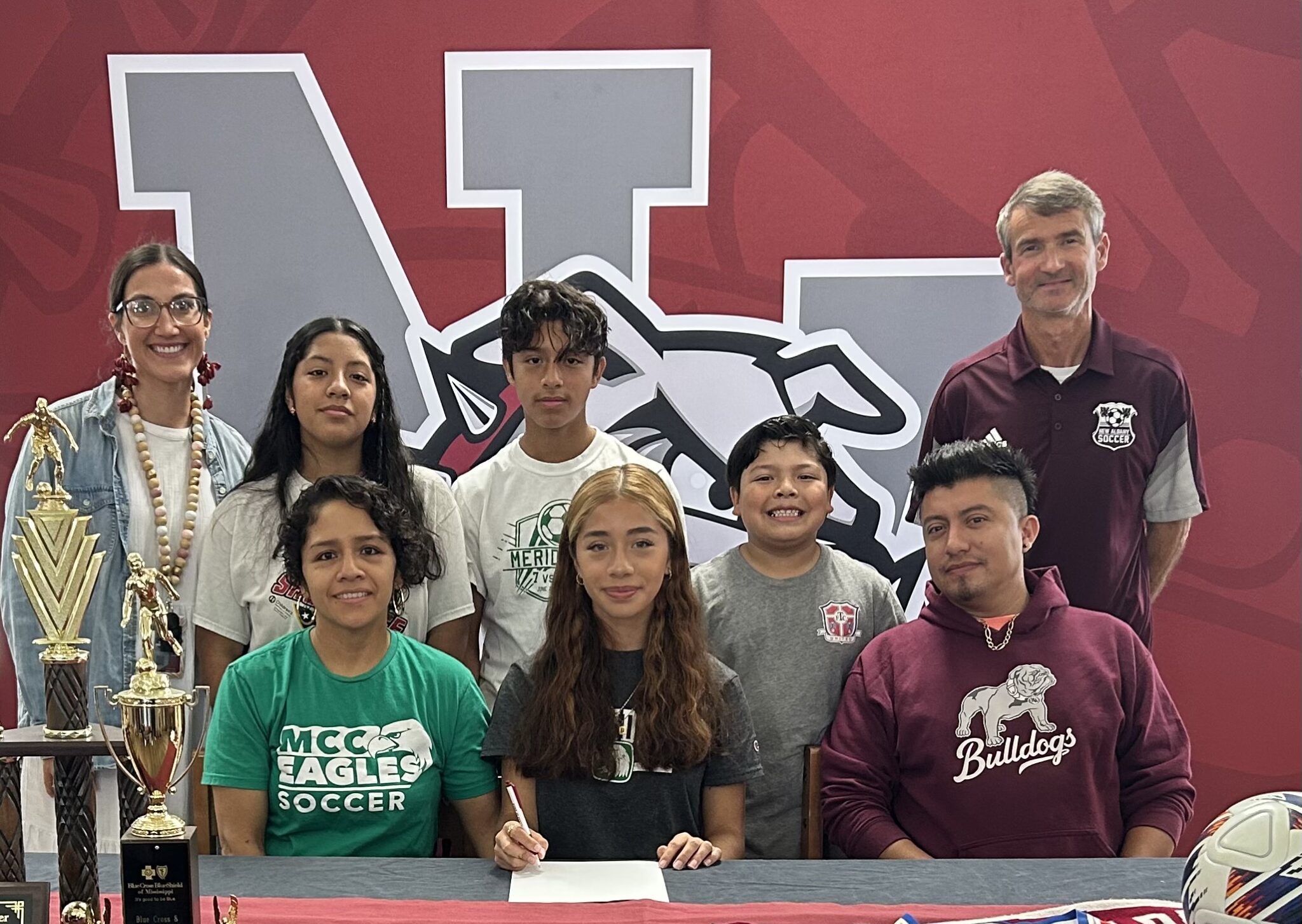 On Wednesday, November 8, New Albany Lady Bulldog Soccer's Ingrid Ojeda signed to play soccer with Meridian Community College. Pictured are front row l-r: Raquel Rodriguez, Ingrid Ojeda, Ethan Ojeda, Ivan Ojeda; back row l-r: NAHS Assistant Coach Katelyn Robbins, Anette Ojeda, Iker Ojeda, and NAHS Head Coach Bert Anderson.